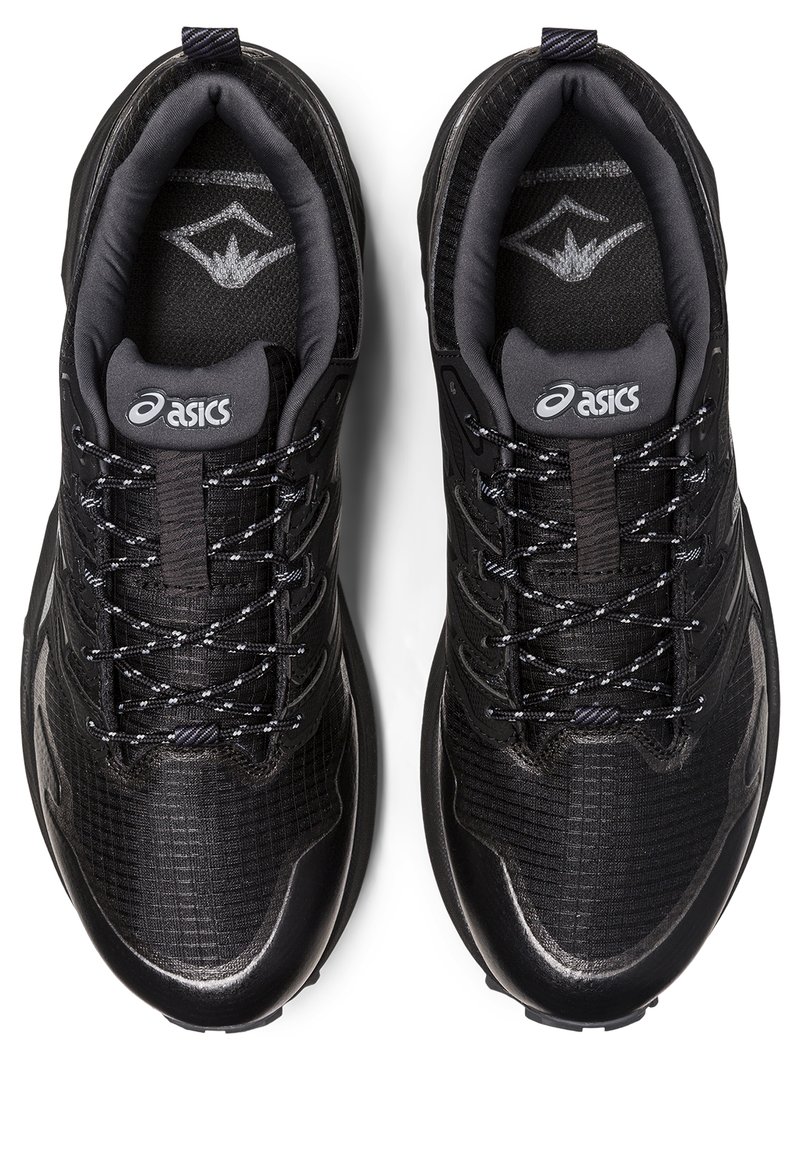 Zapatillas deportivas negras con parte superior de malla texturada, cuello acolchado, acentos grises y cordones con patrón. Presenta un logo en la lengüeta.