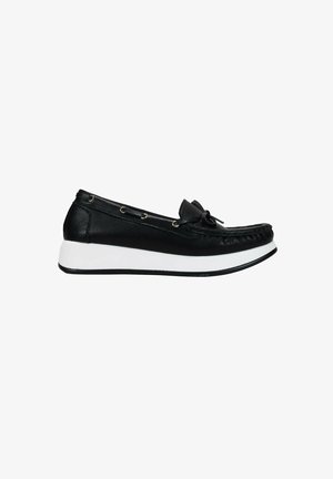 Zapato negro de cuero tipo slip-on con punta redondeada, suela de goma blanca, acento de lazo y ojales decorativos de metal a lo largo del costado.