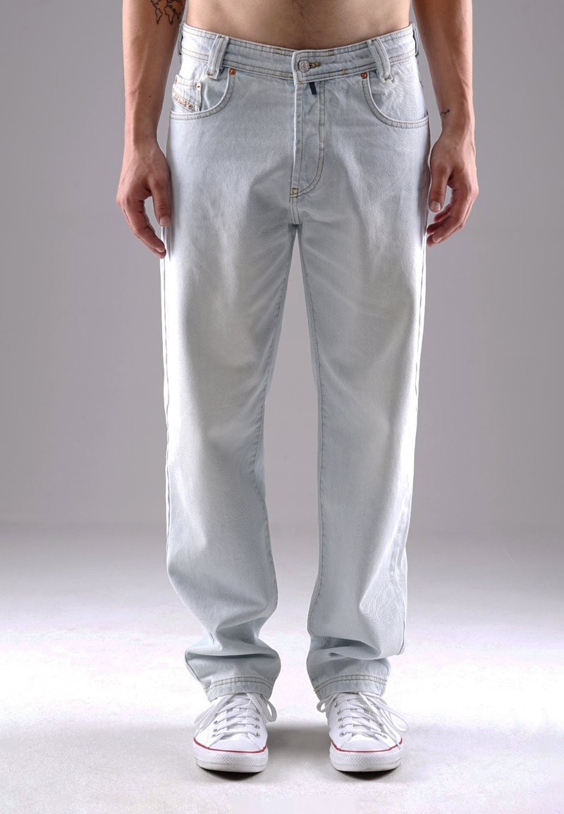 Helle blaue Denim-Jeans mit geradem Bein, ausgestattet mit Fronttaschen, dezenten Ausbleichungen und verstärkten Nähten. Getragen mit weißen Sneakers.