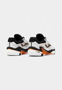 Zapatillas deportivas blancas con acentos negros y detalles naranjas. Material texturizado, cuello acolchado y suela con patrón para tracción.