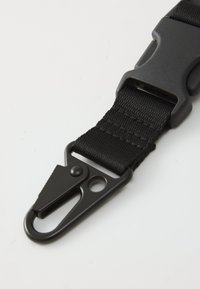 Black nylon strap with a plastic buckle and metal clip. Textured weave and adjustable length feature. Minimalist design and durable materials.