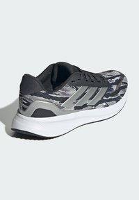 Schwarzer und grauer Sneaker mit einem strukturierten Obermaterial, glatten grauen Akzenten und einer weißen gepolsterten Sohle. Besitzt drei silberne Streifen an der Seite.