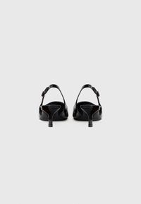 Black patent leather slingback heels with a slender heel, open back design, and adjustable buckle strap. Smooth surface with glossy finish.
