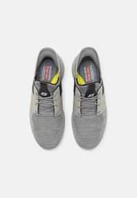 Szürke slip-on sportcipők textúrás hálós felsőrésszel, fekete kiegészítőkkel és fényvisszaverő elemekkel. Szürke fűzős kialakítással és párnázott talpbetéttel rendelkeznek.