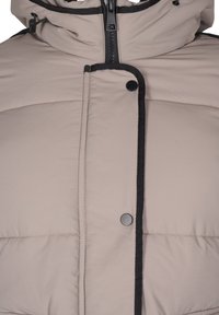 Giacca imbottita beige con colletto alto, dettagli neri, zip frontale e bottoni a pressione. Presenta cuciture diagonali per una texture interessante.