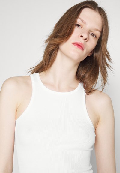 Hvid ribbet tanktop med en tætsiddende design, brede stropper og rund halsudskæring. Glat tekstur uden mærkbare mønstre eller detaljer.