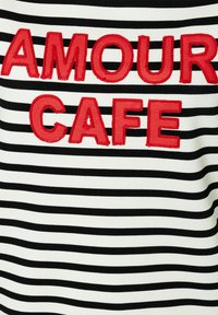Gestreepte zwart-wit stof met gedurfde, rode geborduurde tekst "AMOUR CAFE" in het midden van het ontwerp. Zachte textuur en casual stijl.