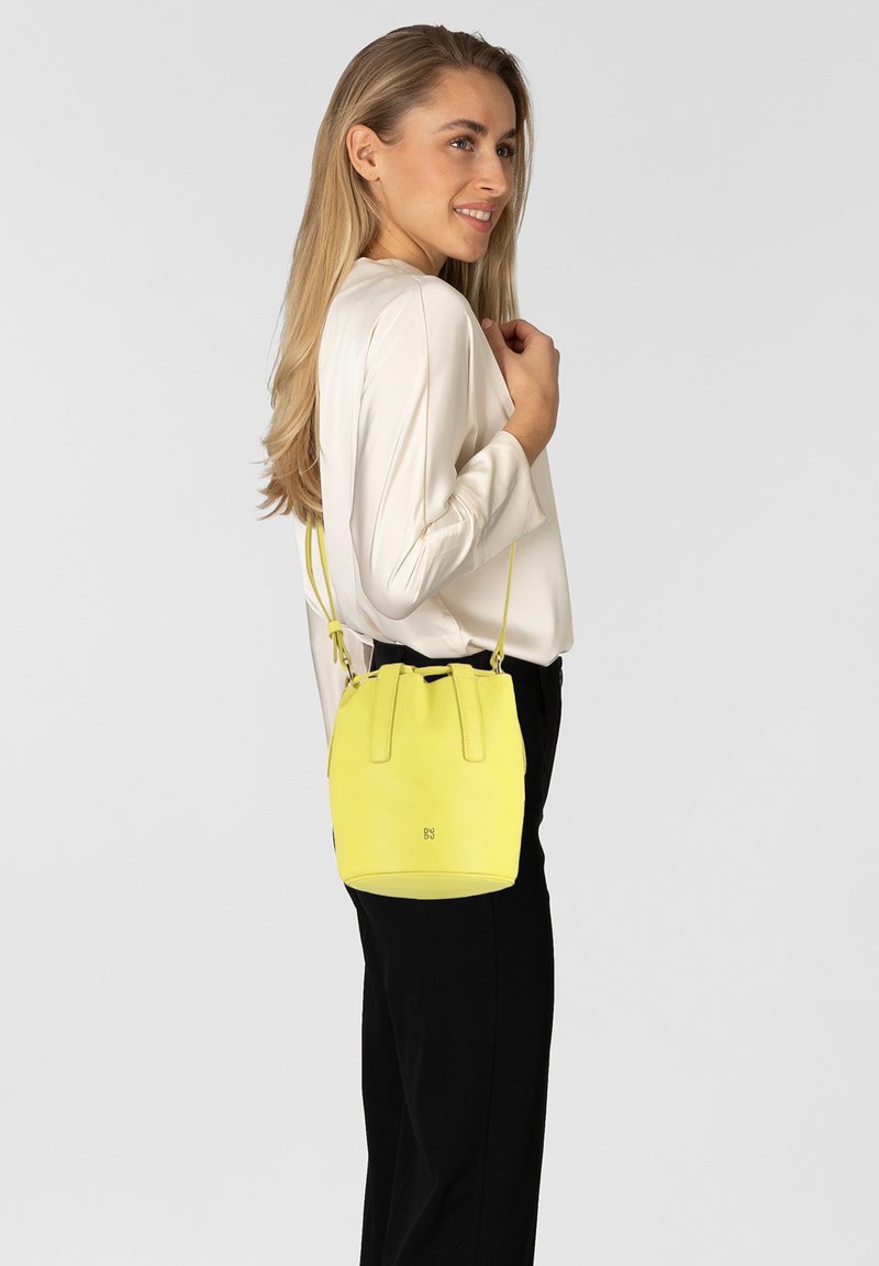 Borsa a secchiello gialla in pelle con finitura testurizzata, due manici superiori e tracolla regolabile. Design minimalista con un discreto dettaglio del logo alla base.
