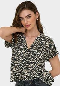 Svartvit kortärmad skjorta med djurtryck, v-ringning och mjukt, lätt tyg.