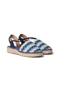 Vevda espadrillos med ett randigt mönster i blått och beige, marinblå accenter och en sula av jute. Öppen baksida med korsade remmar för stöd.