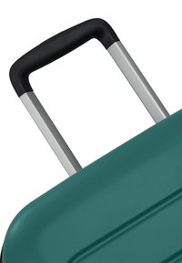 Poignée télescopique avec grip noir étendue d'une valise rigide bleu sarcelle.