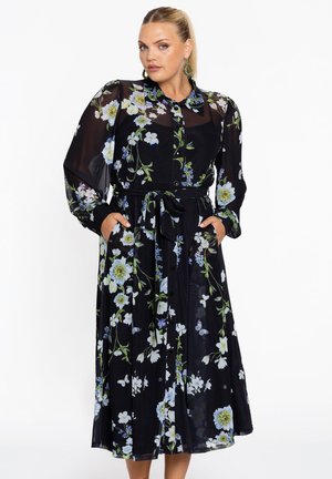 Robe noire à motifs floraux avec de longues manches transparentes, bouton devant et taille cintrée. Présente des motifs floraux verts et bleus, avec des poches latérales.