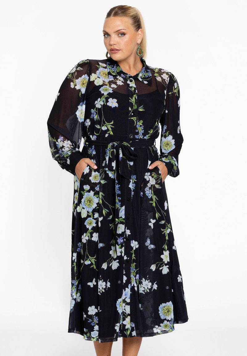 Schwarzes Blumenkleid mit langen transparenten Ärmeln, Knopfleiste und taillierter Taille. Mit grünen und blauen Blumenmustern sowie seitlichen Taschen.