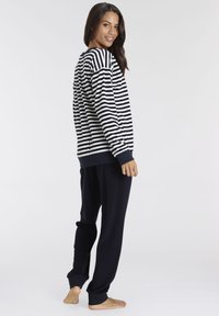 Sudadera de manga larga a rayas en navy y blanco, combinada con joggers navy. Textura suave con puños y cinturilla acanalados.