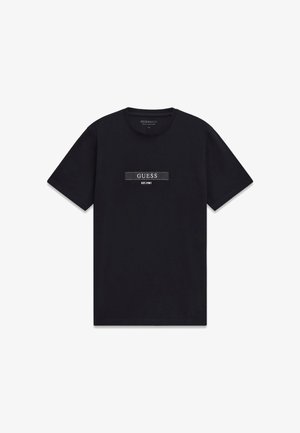 Camiseta de algodón negra con mangas cortas y cuello redondo, que presenta un parche de logo horizontal con "GUESS EST. 1981" en blanco y gris.