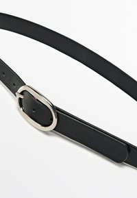 Zwarte leren riem met een gladde textuur, dunne profiel en een ovale zilveren gesp met een prong sluiting. Vijf verstelgaten.