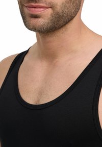Top nero senza maniche con scollatura rotonda, realizzato in un materiale liscio e elasticizzato. Presenta cuciture visibili lungo i bordi e una vestibilità aderente.