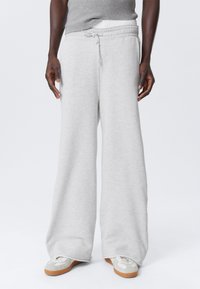 Lichtgrijze wijde sweatpants met een trekkoord in de taille, gemaakt van zacht materiaal. Heeft een gestructureerde afwerking en een minimalistisch ontwerp.