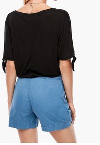 Svart lös passform topp med korta ärmar och knyt detaljer, matchad med ljusblå denimshorts. Enkelt design med avslappnad skärning.