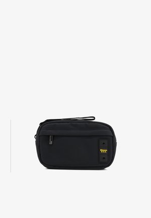 Pochette da viaggio nera in nylon con chiusura a zip, tasca frontale e patch giallo. Presenta una finitura testurizzata e una maniglia superiore per il trasporto.