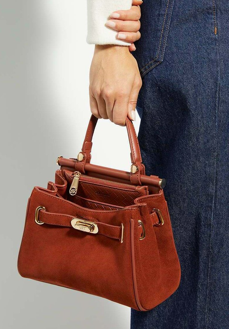 Burnt orange suede handbag with gold hardware, top handles, and an interior zip pocket. The bag features a structured shape and detachable accents.