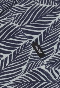 Marineblauwe en lichtblauwe stof met een bladenpatroon, getextureerde weefsel, met een klein "J&JOY" label zichtbaar in de hoek.
