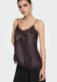 Tmavě fialový saténový top na ramínka s jemnou černou krajkou podél výstřihu a lemu, s tenkými nastavovacími ramínky.