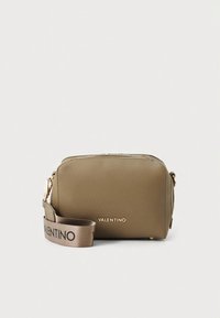 Tannfarget skinnveske med crossbody-stropp i gullfarget metall og logo-preget bånd, med glidelåslukking og rektangulær form.