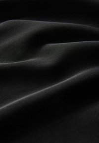 Tessuto nero con una texture liscia e leggermente lucida, che presenta pieghe morbide e una leggera lucentezza. Materiale elasticizzato e leggero.