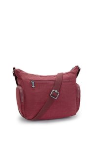 Röd tyg crossbody-väska med justerbar rem, fack med dragkedja fram och två sidofack med dragkedja, isolerad på vit bakgrund.