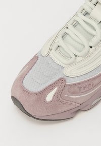 Baskets avec une partie supérieure en mesh gris clair, des accents en suède pâle et un capuchon de orteil rose-violet. Présente des lacets blancs et un branding ton sur ton.