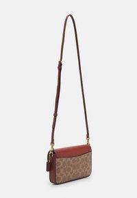 Crossbody taška s hnědou koženou horní částí a béžovým vzorovaným plátěným dnem, se zlatými kovovými detaily a nastavitelným popruhem.