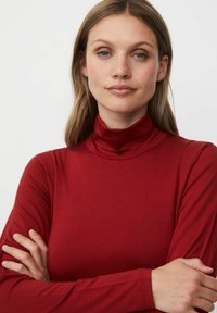 Rode lange mouw turtleneck top met een nauwsluitende kraag en een gladde textuur, voorzien van lange mouwen en een eenvoudig, minimalistisch ontwerp.