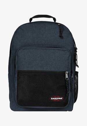 Mochila de tela azul oscuro con un bolsillo de malla en la parte frontal, cierres de cremallera y un asa superior. Presenta un logo de marca y correas ajustables.