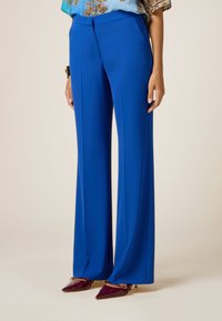 Blue, wide-leg trousers made of smooth fabric. Features a flat front and sleek, tailored design with a high waist.