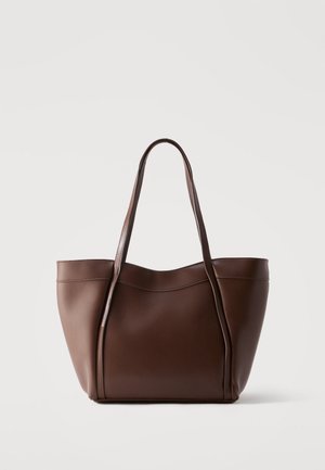 Sac fourre-tout en cuir marron avec deux bretelles d'épaule et un design simple et lisse sur un fond clair uni.