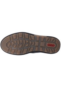 Suela de zapatilla negra con una superficie de goma texturizada, que presenta profundas estrías para un mejor agarre y un acento de marca roja cerca del talón.