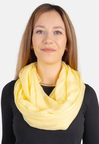 Textured yellow scarf wrapped in a loop, made of lightweight fabric, featuring a soft finish and casual drape around the neck.