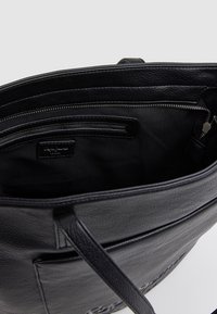 Musta nahkainen kantokassi, jossa on vetoketjullinen sisäosasto, sileä pinta, tukevat hihnat ja hienovarainen logo-nyrkkileima etupuolella.