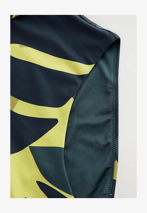 Svetlorjavi material za kopalke v temno modri barvi z abstraktnimi rumenimi in zelenimi listnatimi vzorci. Gladka tekstura s prilegajočim dizajnom in šivanim robom.