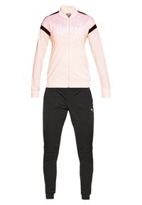 Veste de sport rose clair zippée avec des rayures diagonales noires sur les manches, associée à un pantalon de sport noir ajusté avec un petit logo blanc.