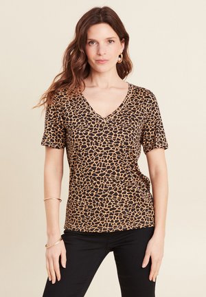 T-shirt à manches courtes en v, dans un imprimé animal brun et noir, présentant une texture douce et une coupe décontractée. Accent de quincaillerie minimal.