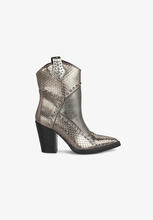 Stivali da cowboy metallici con motivo a serpente testurizzato, dettagli argento, punta affusolata e tacco spesso nero. Borchie decorative vicino alla parte superiore.
