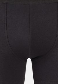 Boxer shorts en coton noir avec un design ajusté, présentant une texture lisse et une ceinture élastique. Coutures visibles le long des seams.