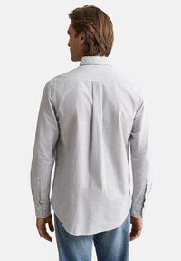 Herenoverhemd met lange mouwen, uitgevoerd in blauw-witte verticale strepen, een button-down kraag en een rechte achterkant met een plooi detail.