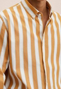 Camicia a righe gialle e bianche con colletto, caratterizzata da un tessuto testurizzato e un design slim fit. Due bottoni visibili sul colletto.