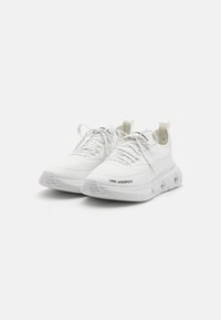 Scarpe da ginnastica bianche con tomaia texturizzata, chiusura con lacci, collo imbottito e dettaglio del logo sul lato e sulla linguetta. Suola in gomma spessa.
