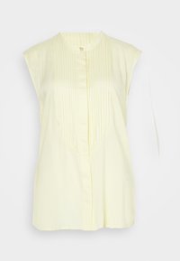 Lys gul uten ermer bluse med plissert front, rund halslinning, og midtknapplukking, laget av lett materiale.