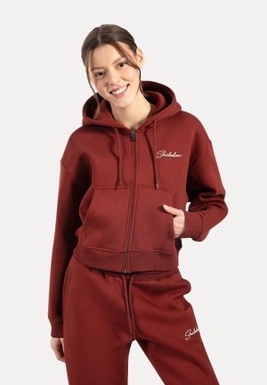 Haut à capuche zippé bordeaux avec une poche avant, des poignets côtelés et un logo brodé. Fabriqué en tissu doux avec une coupe décontractée.