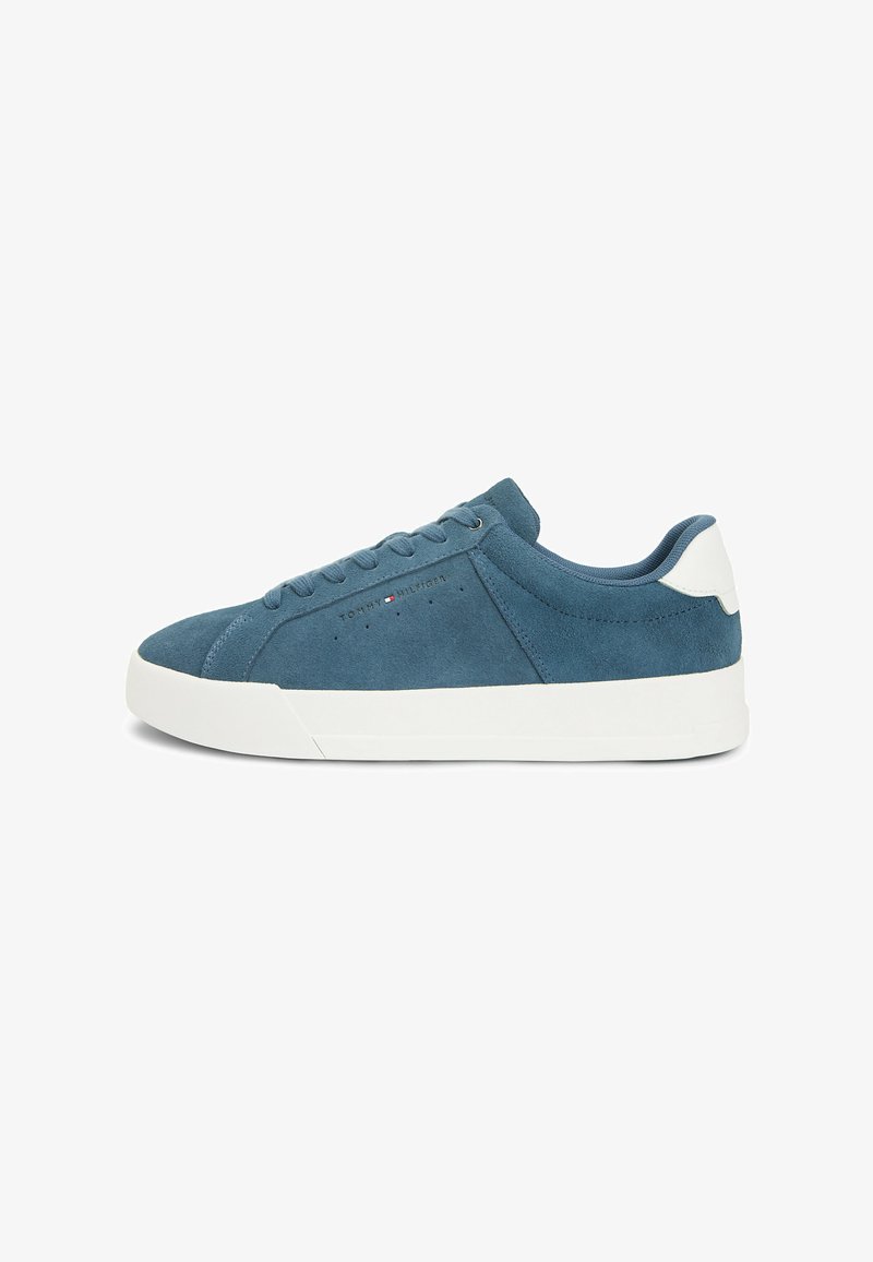 Baskets basses en daim bleu avec semelle blanche et languette au talon, design à lacets, et petit logo Tommy Hilfiger sur le côté.